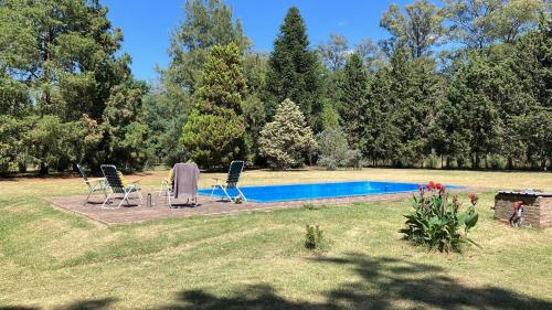 a swimming pool with two chairs and a table at Gran Quinta en Mercedes con piscina in Mercedes