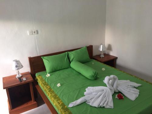 a green bed with green sheets and towels on it at Linggy Homestay in Nusa Lembongan