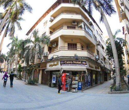 een groot gebouw met palmbomen ervoor bij Cairo Hotel فندق القاهرة in Caïro
