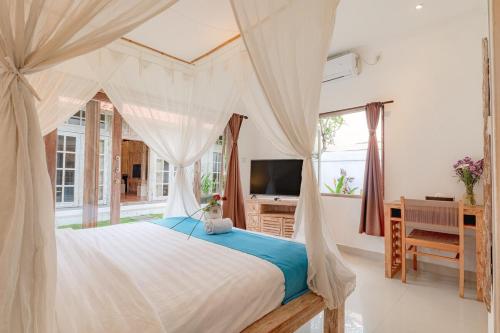 a bedroom with a canopy bed with a desk and a television at Villa Toto Seminyak in Seminyak