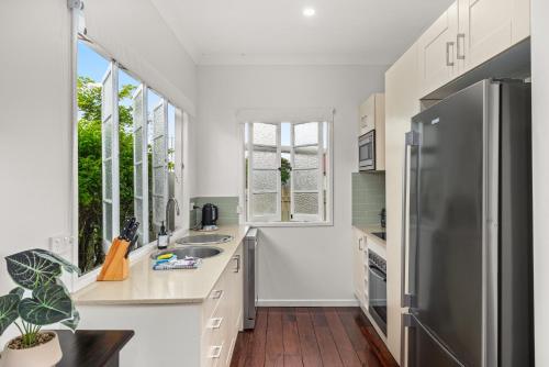 a kitchen with white counters and a stainless steel refrigerator at Charming 1-Bed Cottage with Garden Retreat in Bald Hills