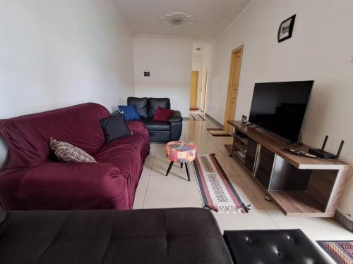 a living room with a purple couch and a flat screen tv at Linda casa para COP 30 in Belém