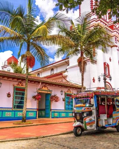 a vehicle parked in front of a building with palm trees at DESCANSO DEL ARRIERO - Su Mejor Descanso en Guatapé in Guatapé