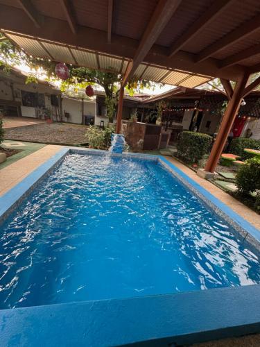a large blue swimming pool with a water fountain at Villas Ela en Bahía Ballena,Uvita Hermosas habitaciones privadas grandes, piscina, cocina, jacuzzi, aire acondicionado, tv y baño privado in Uvita