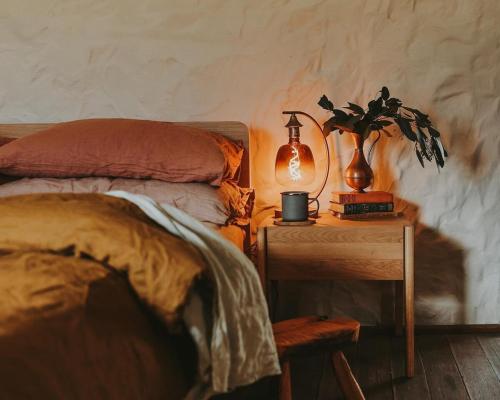 a bedroom with a bed and a table with a plant at Simplistic Luxury Cottage, Ross in Ross
