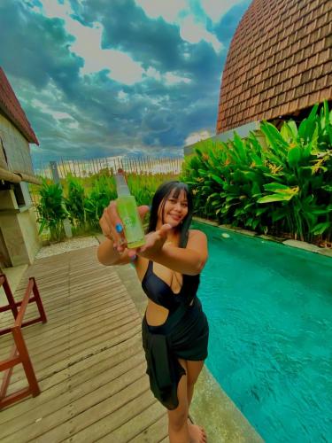 a woman standing next to a pool with a drink at Bhumi Lovina Residence & Villa in Singaraja