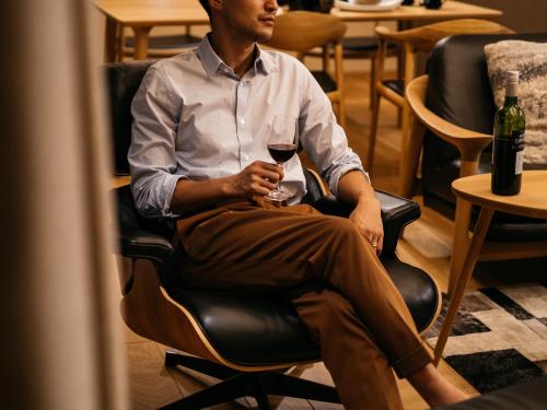 a man sitting in a chair with a glass of wine at 瀬戸内ゴルフリゾートヴィラ in Takekara