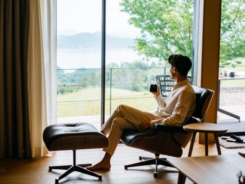 a man sitting in a chair looking out a window at 瀬戸内ゴルフリゾートヴィラ in Takekara