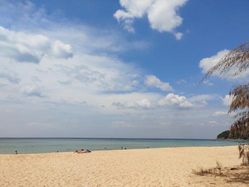 a beach with people in the water and a cloudy sky at Suite of Naithon beachfront apartment in Nai Thon Beach