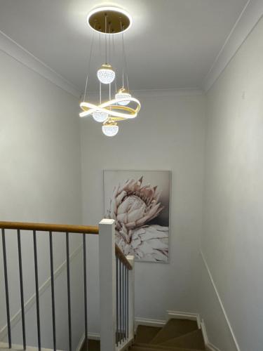a staircase with two chandeliers and a painting on the wall at Serenity Stay Brisbane in North Lakes