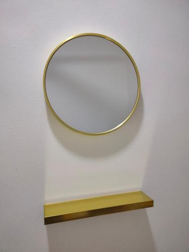 a mirror on a wall with a wooden shelf at Puteri Homestay in Kangar