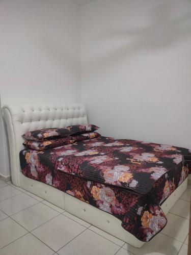 a bedroom with a bed with a floral quilt at Puteri Homestay in Kangar