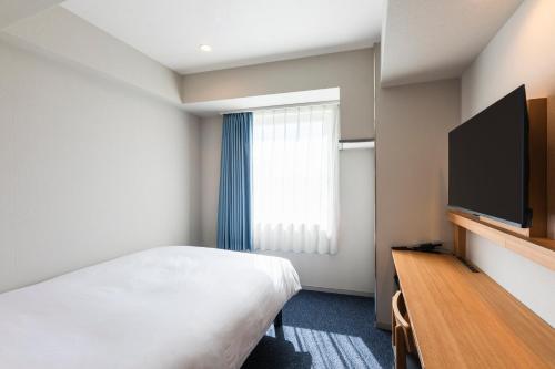 a hotel room with a bed and a flat screen tv at Sotetsu Fresa Inn Yokohama Totsuka - Renovated in March 31st 2025 in Yokohama