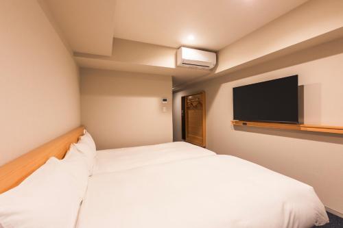 a hotel room with two beds and a flat screen tv at Sotetsu Fresa Inn Yokohama Totsuka - Renovated in March 31st 2025 in Yokohama