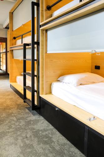 two bunk beds in a dorm room with white sheets at The Capsule Hotel in Sydney