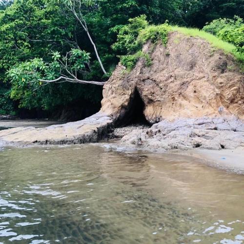 a cave in the side of a mountain next to the water at Casa Celeste Río Grande in Paquera
