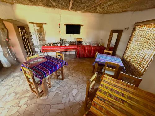 a room with two tables and chairs and a television at Atacama Lodge Rukazen Rústico in San Pedro de Atacama