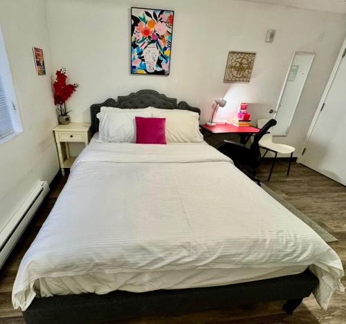 Un dormitorio con una gran cama blanca con una almohada roja. en Micro Studio Apartment 10 Minutes Walk To University of Washington, en Seattle