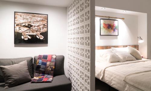 a bedroom with a bed and a couch next to a wall at attitude on granville in Hong Kong