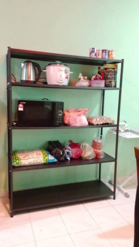 a black shelf with a microwave on it at Homestay Taman Delima Paka in Kampong Gong Gemia