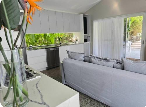a living room with a couch and a kitchen at Cruisin In Byron in Byron Bay