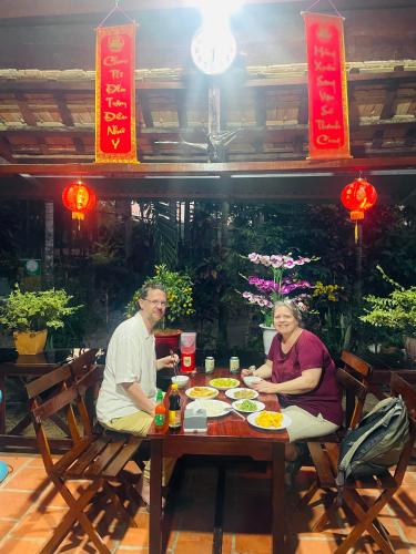 カッティエンにあるForest Side Ecolodgeの食べ物を持ってテーブルに座っている男性と女性