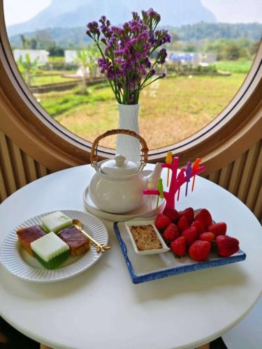 a table with two plates of food and a vase of flowers at หลงเขา Chiang Dao in Ban Thung Lakhon
