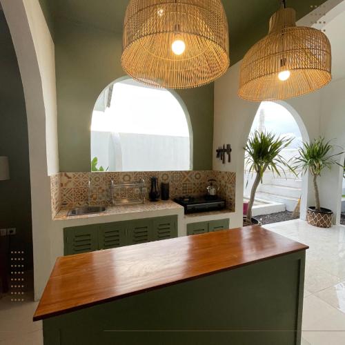 a kitchen with two chandeliers and a counter top at Villa Ganesh by Suasana Villa in Jarakan