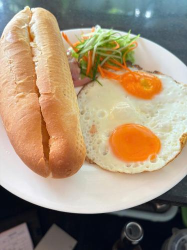 a plate with a fried egg and a hot dog at Vi TamCoc Hotel in Ninh Binh