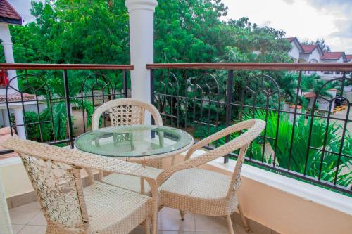 a glass table and two chairs on a balcony at Heavenly Homes in Malindi