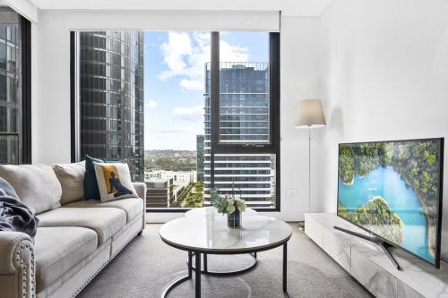a living room with a couch and a tv at Waterview 1bedroom Plus Study Room at Wentworth Point in Sydney