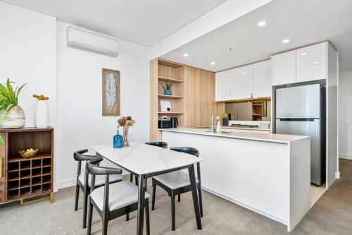 a kitchen with a table and chairs and a refrigerator at Waterview 1bedroom Plus Study Room at Wentworth Point in Sydney