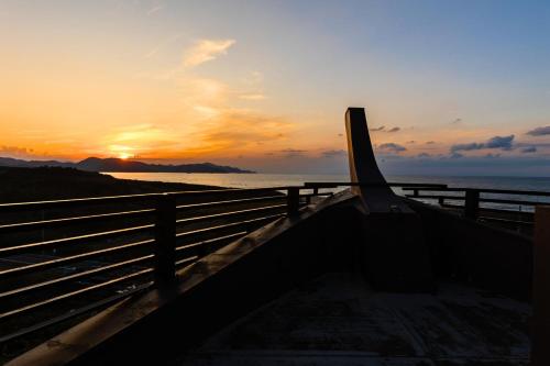 a sunset over the ocean with a fence at Ichiboukan Hanare Kai in Kyotango