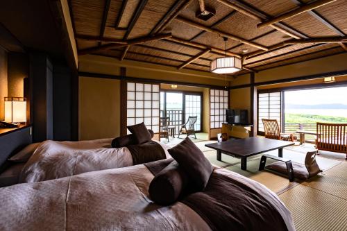 a bedroom with two beds and a living room with a table at Ichiboukan Hanare Kai in Kyotango