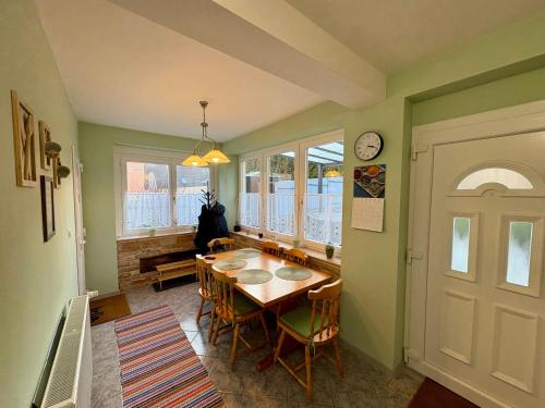 a dining room with a table and chairs and a clock at Igali Varázs Apartman 150 méter a fürdőtől in Igal