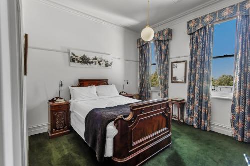 a bedroom with a large bed and two windows at Yarra Valley Grand in Yarra Glen