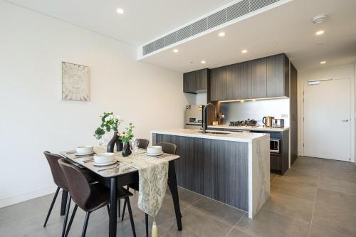a kitchen and dining room with a table and chairs at Lidcombe Apt Near Olympic Park Train in Sydney