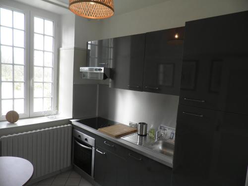 - une cuisine avec des placards noirs et un évier dans l'établissement Victoria, à Tracy-sur-Mer