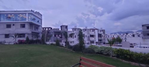 a row of white buildings with a green field in front at Aarambh Home stay in Garudeshwar