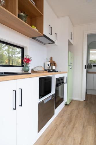 a kitchen with white cabinets and stainless steel appliances at ARBY - Irvine Wines Tiny Home in Craneford