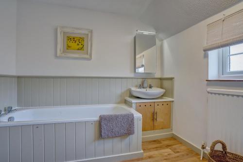 une salle de bain avec une grande baignoire et un lavabo dans l'établissement Rose Cottage by Winterton Cottages, à Winterton-on-Sea