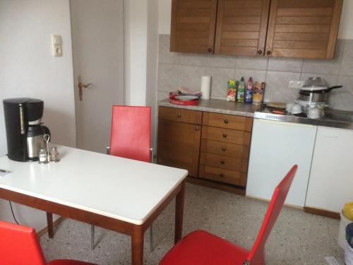 a kitchen with a white table and red chairs at Zur Krone in Wolfsegg
