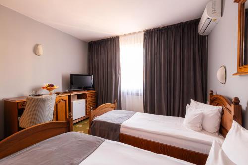 a hotel room with two beds and a television at Hotel Brilliant Meseș in Zalău