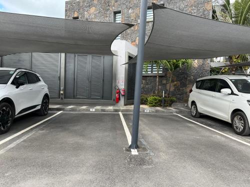 two white cars parked in a parking lot at Beach front penthouse in Pereybere in Grand Baie