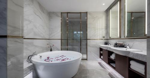 a bathroom with a white tub and two sinks at Xinghuacun Hotel in Pingyao