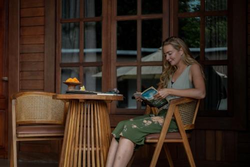 a woman sitting in a chair reading a book at Tattva Ubud Retreat & Wellness in Ubud