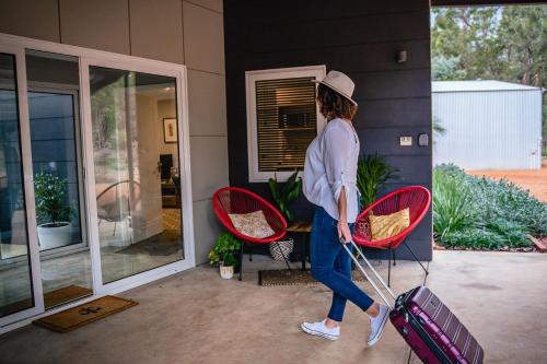 a woman walking with her luggage outside a house at Red Tail Retreat in Collie