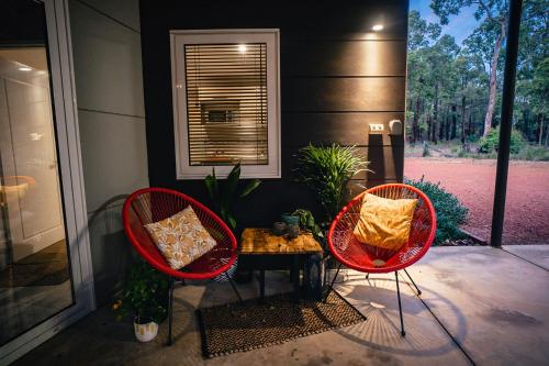 two red chairs and a table on a porch at Red Tail Retreat in Collie