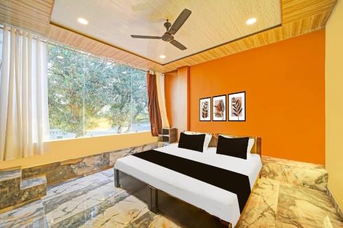 a bedroom with a bed with an orange wall at Hotel O Dwarka Hotel And Restaurant in Dīp