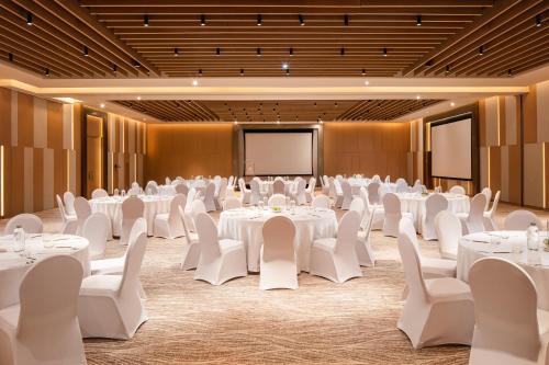 a conference room with white tables and chairs and a projection screen at Holiday Inn & Suites - Dubai Science Park by IHG in Dubai